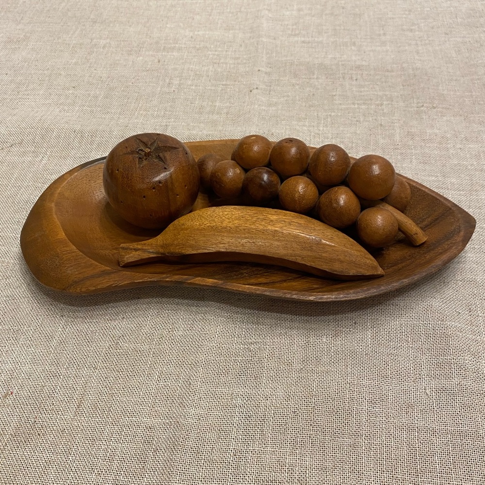 Wooden fruit (grapes, apple, banana) on wooden plate.